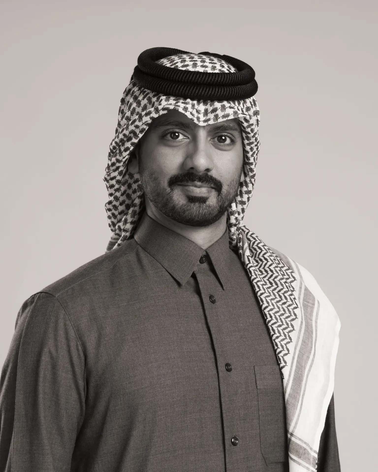 Black and white studio portrait of a young Qatari man in patterned shemagh, Doha