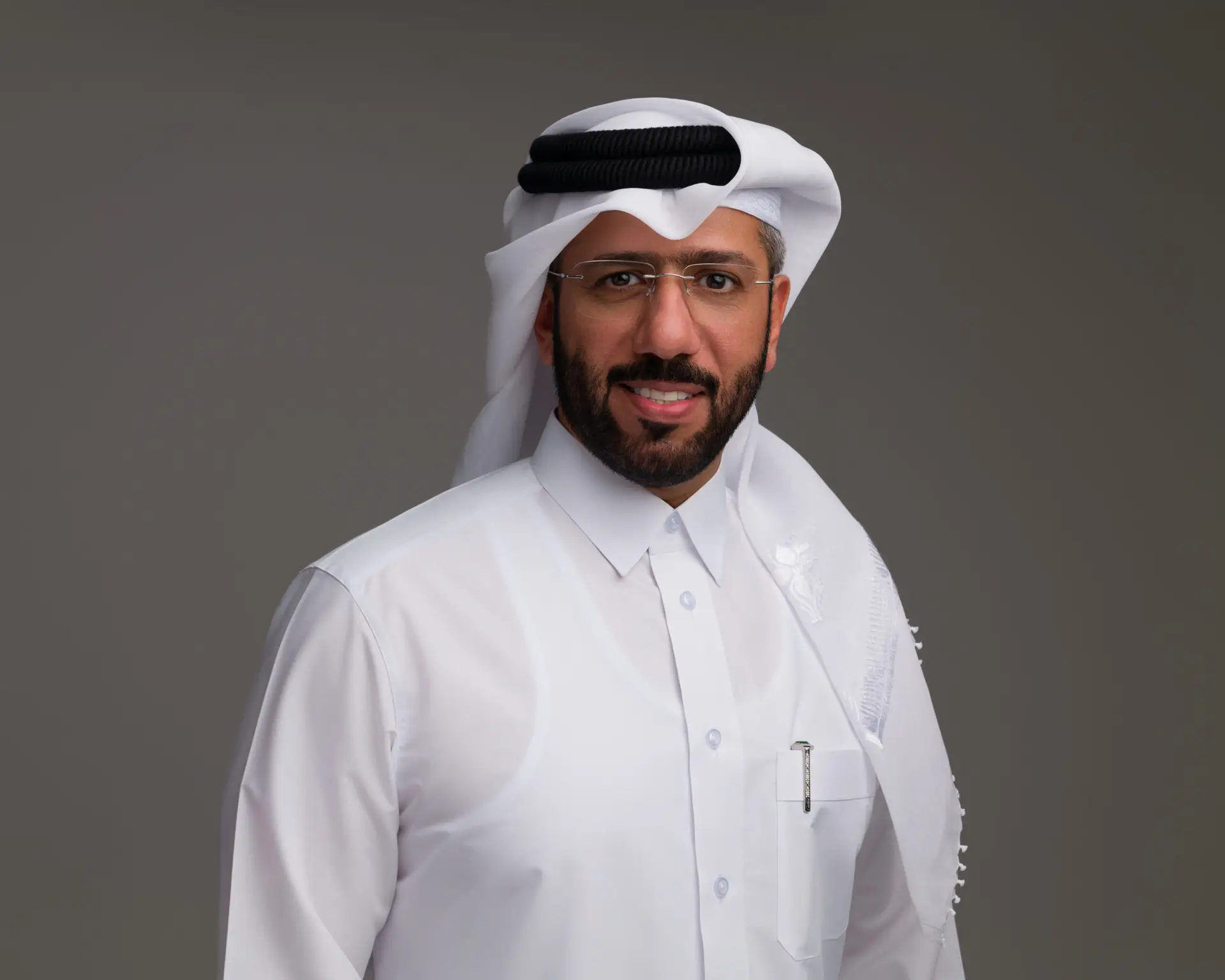 Executive headshot of a Qatari man in a white thobe and ghutra, photographed on a grey backdrop in our Doha studio.